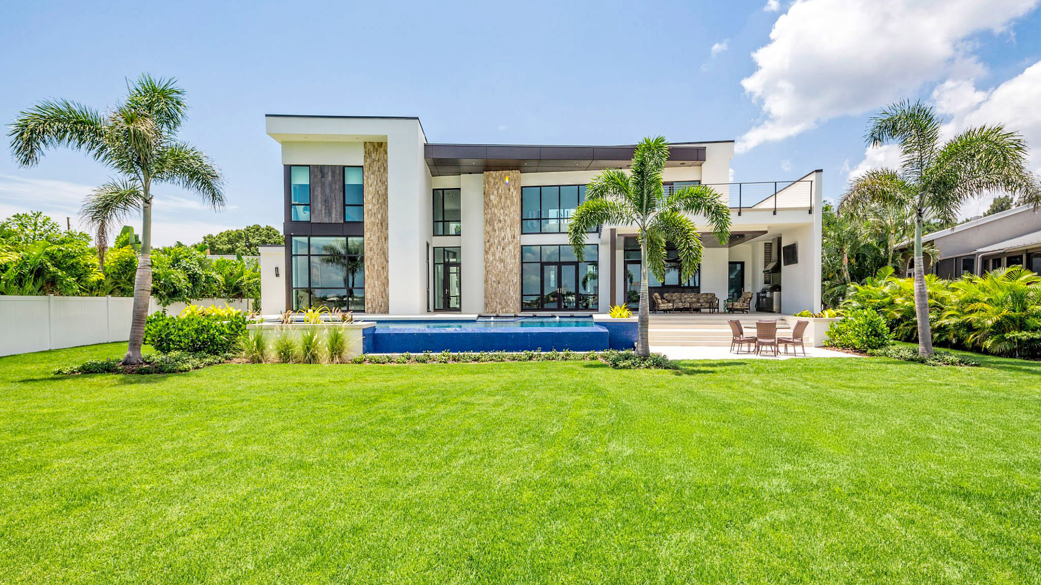 A beautiful modern home with landscaped backyard, swimming pool with waterfall and spa including an outdoor sitting area with TV.